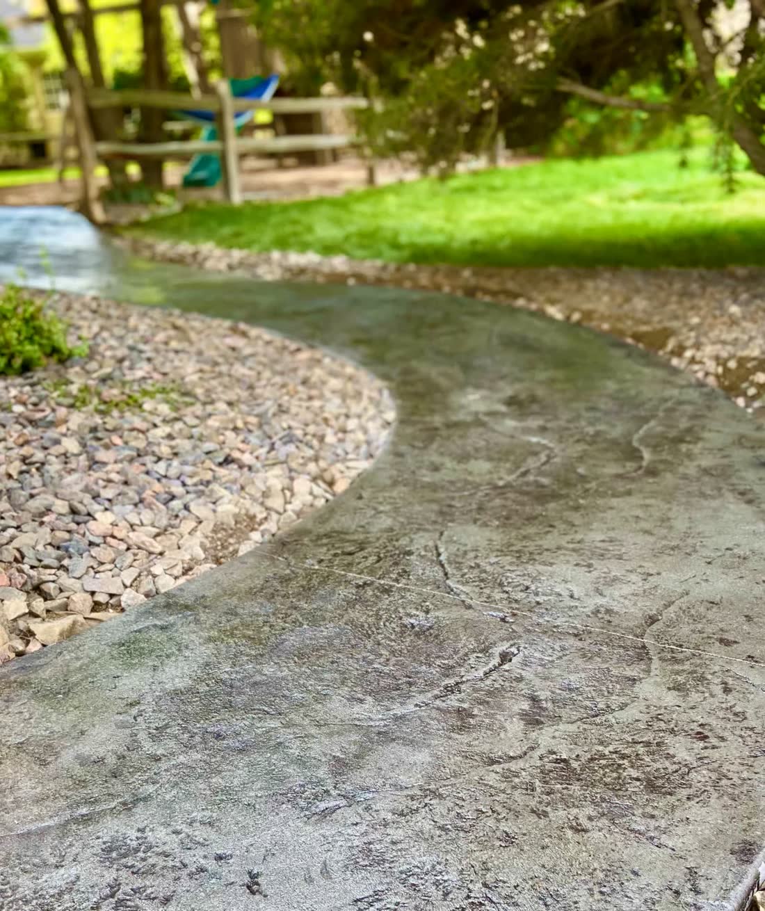 Curved concrete garden path with a river-rock border