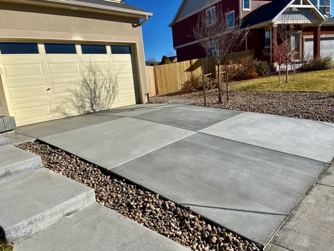 Wide new driveway with concrete steps and river-rock border
